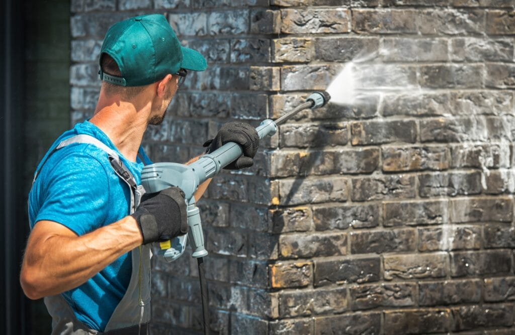 Brick building cleaning with a power washer.